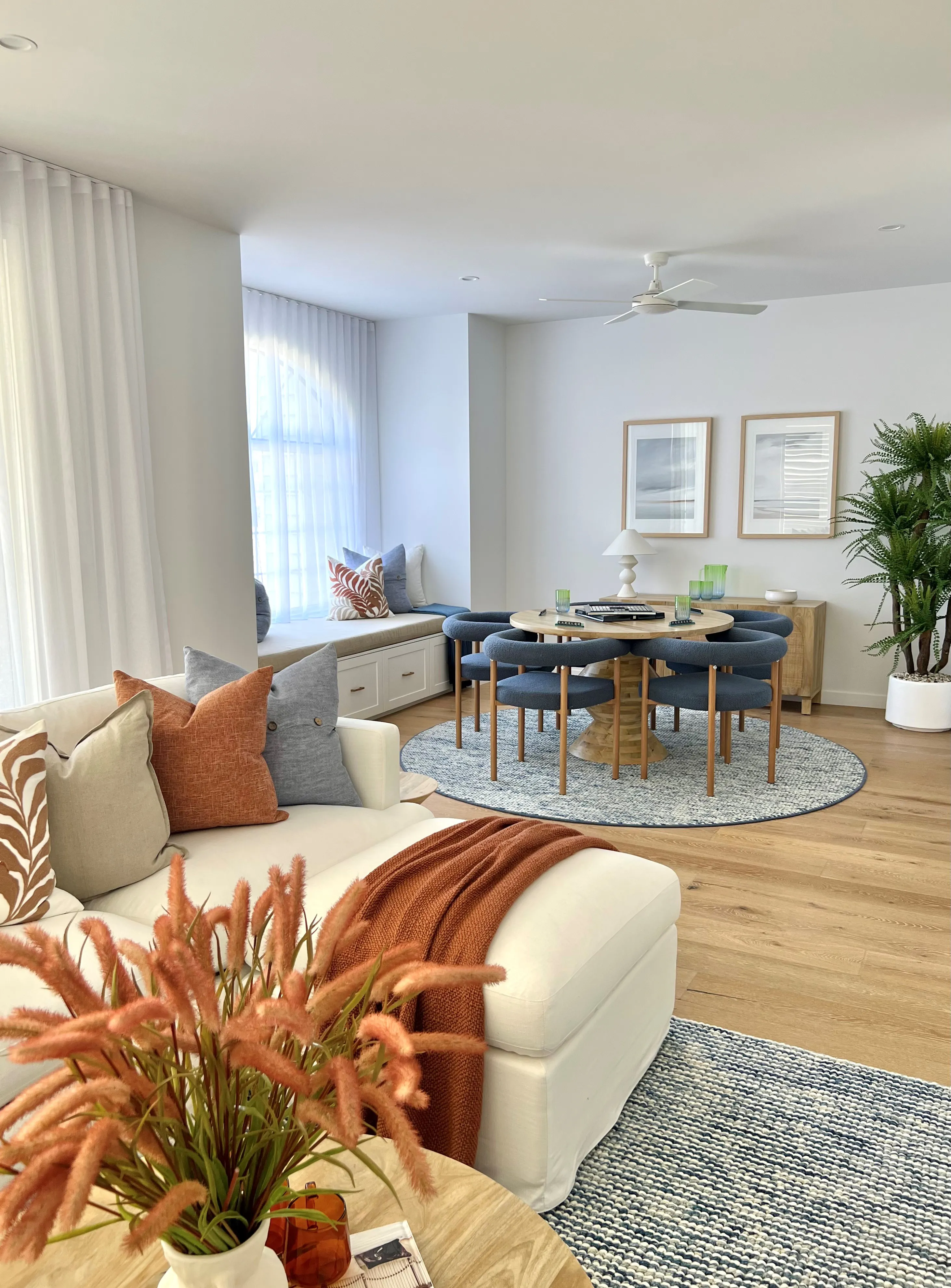 Family room with cream sofa, blue upholstered dining chairs and woven round rug